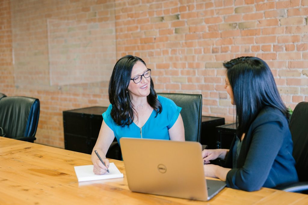 Dwie nauczycielki rozmawiają przy stole na tle ceglanej ściany