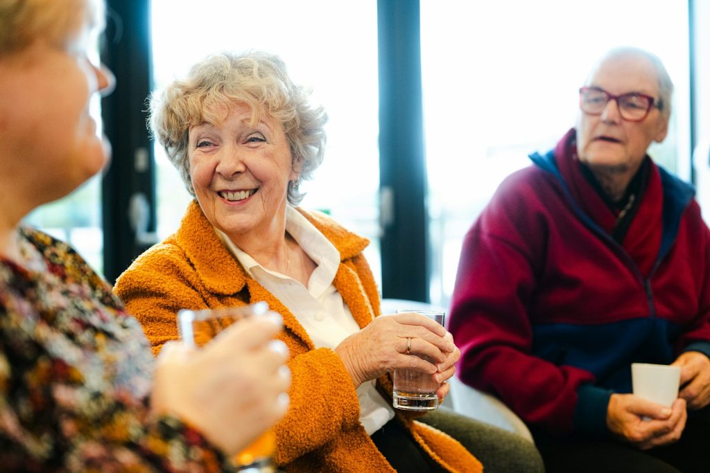 Seniorzy rozmawiają i uśmiechają się podczas spotkania