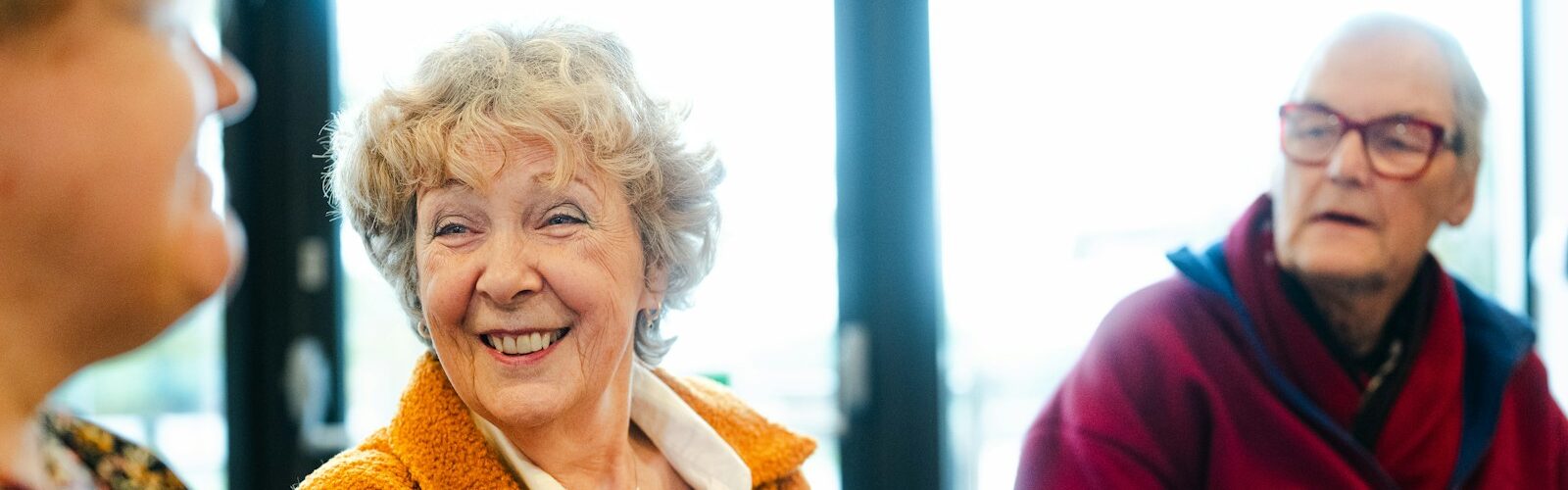 Seniorzy rozmawiają i uśmiechają się podczas spotkania